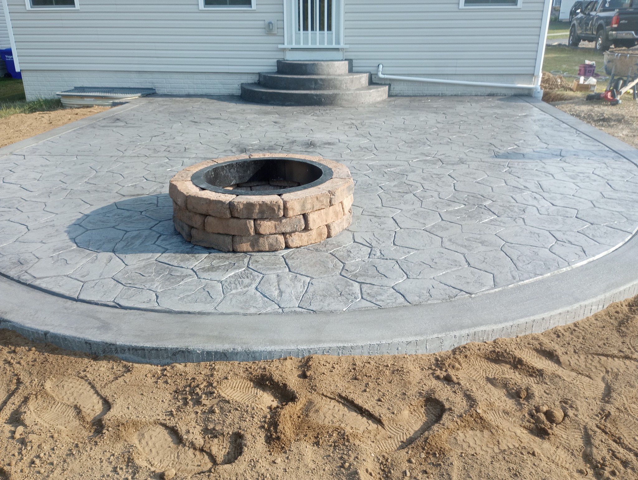 Stamped concrete patio with a circular stone fire pit