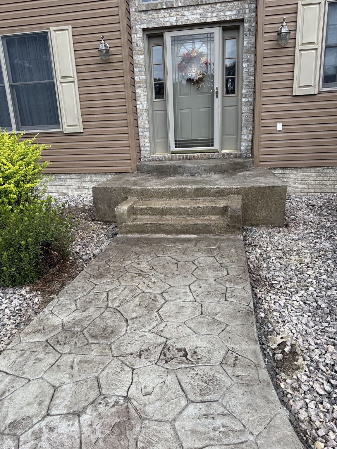 Stamped concrete front walkway leading to exterior steps