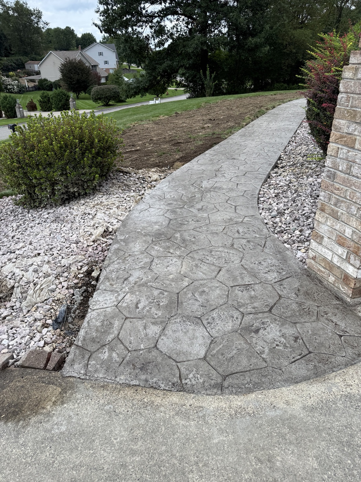Curved stamped concrete walkway through landscaping