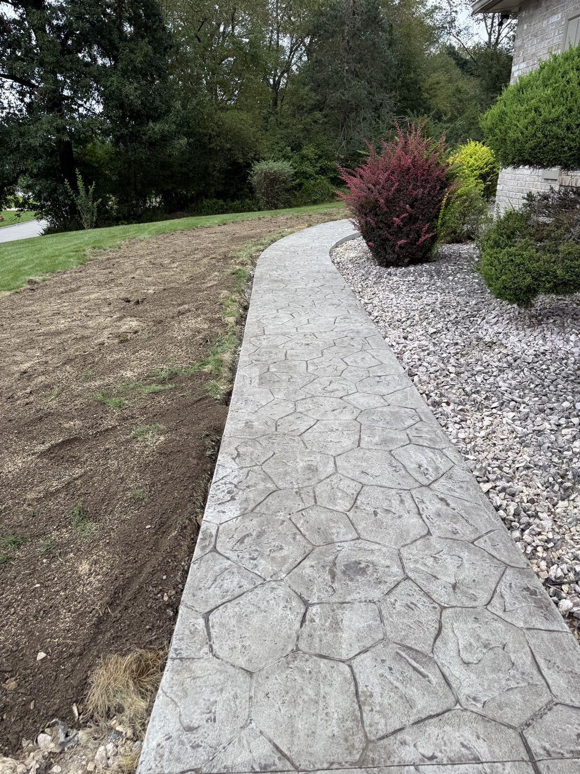 Finished stamped concrete path with stone landscaping