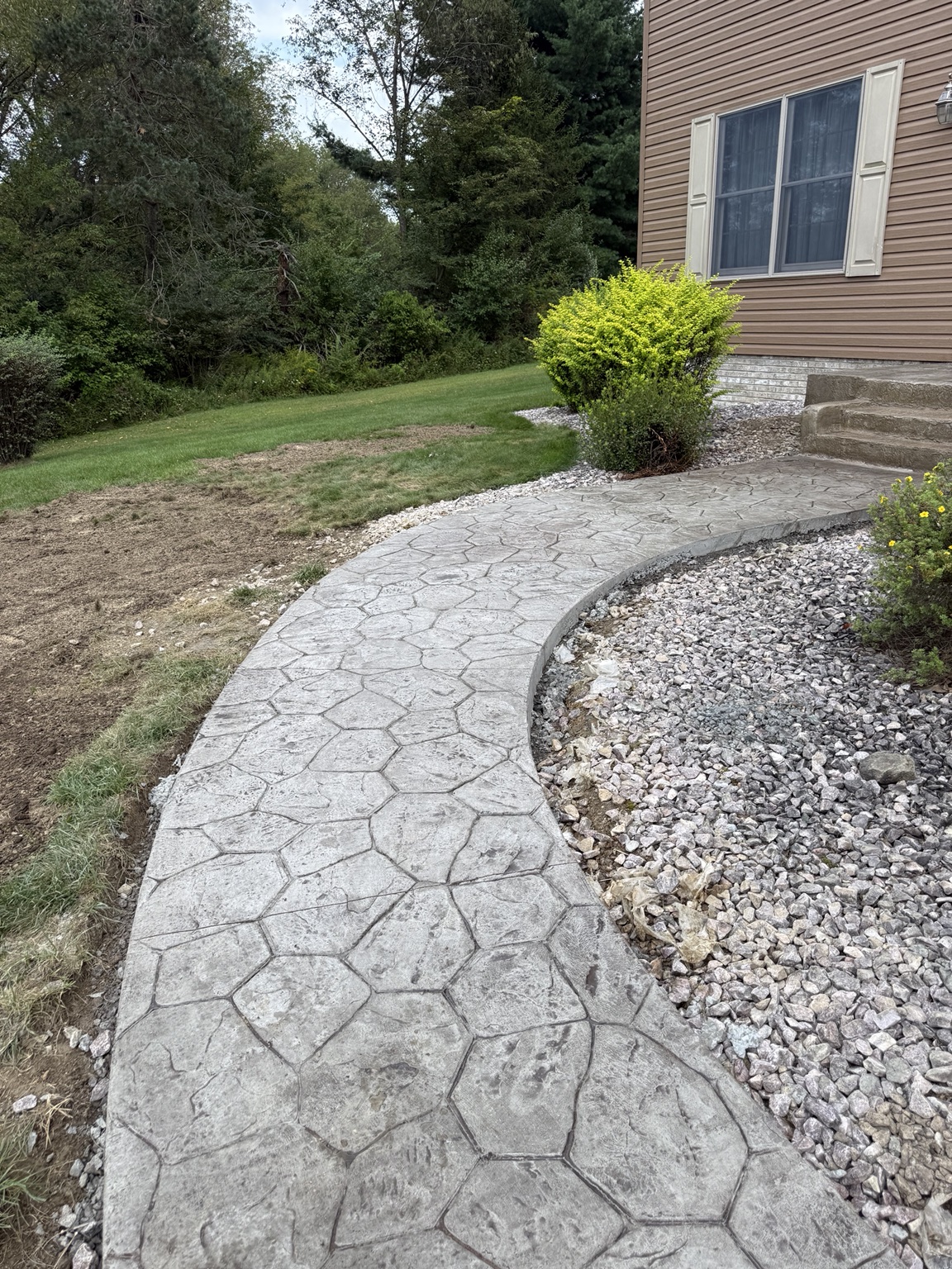 Curved stamped concrete path beside a home